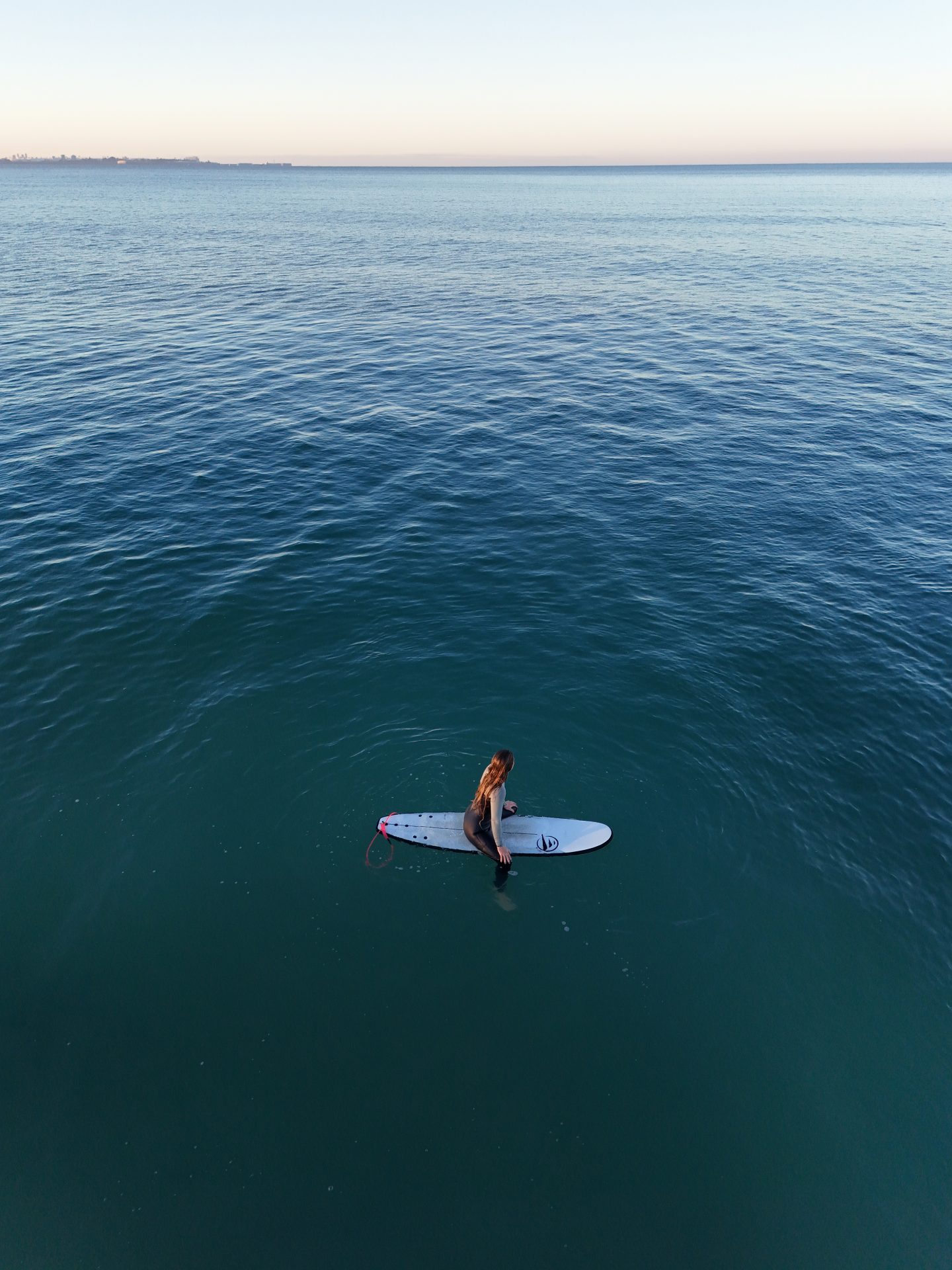 Surfista en medio del mar sobre tabla Fly, verano tranquilo y conexión con el océano.