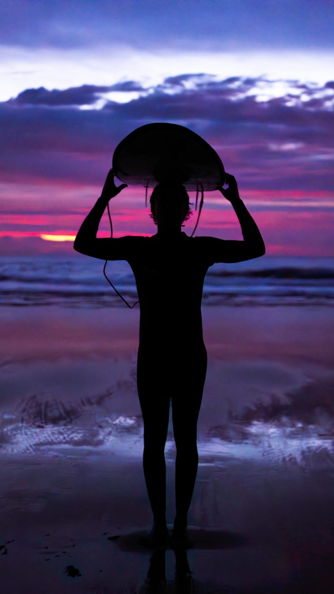 Surfista al atardecer sosteniendo su tabla frente al mar